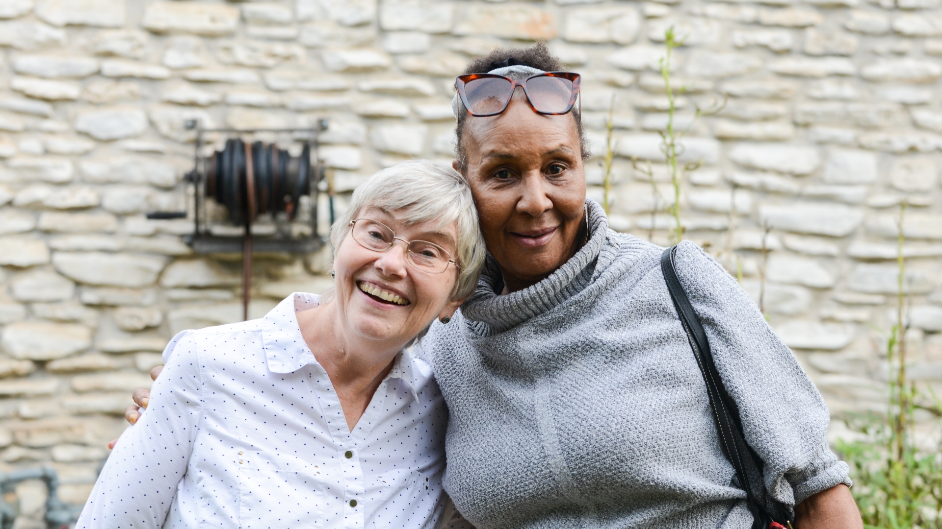 Two friends and members of the Garden Club are side-hugging and smiling.